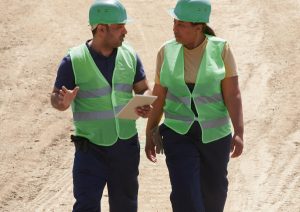 Two people in hi-vis walking on construction site.